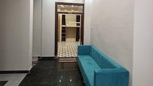Un corridoio moderno con un divano blu, un lampadario dal design geometrico e un pavimento a scacchi.