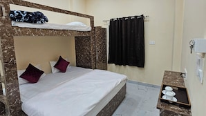 A room with a bunk bed, a ceiling fan, a small shelf with cups, and a curtain. - Kashi Vandanam (Varanasi)