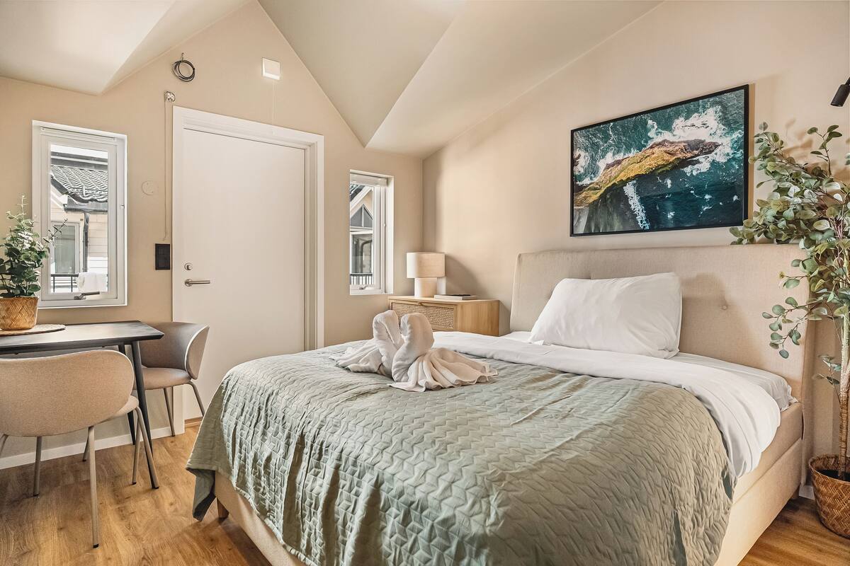 Un dormitorio con una cama, un escritorio, una silla y una planta en maceta.