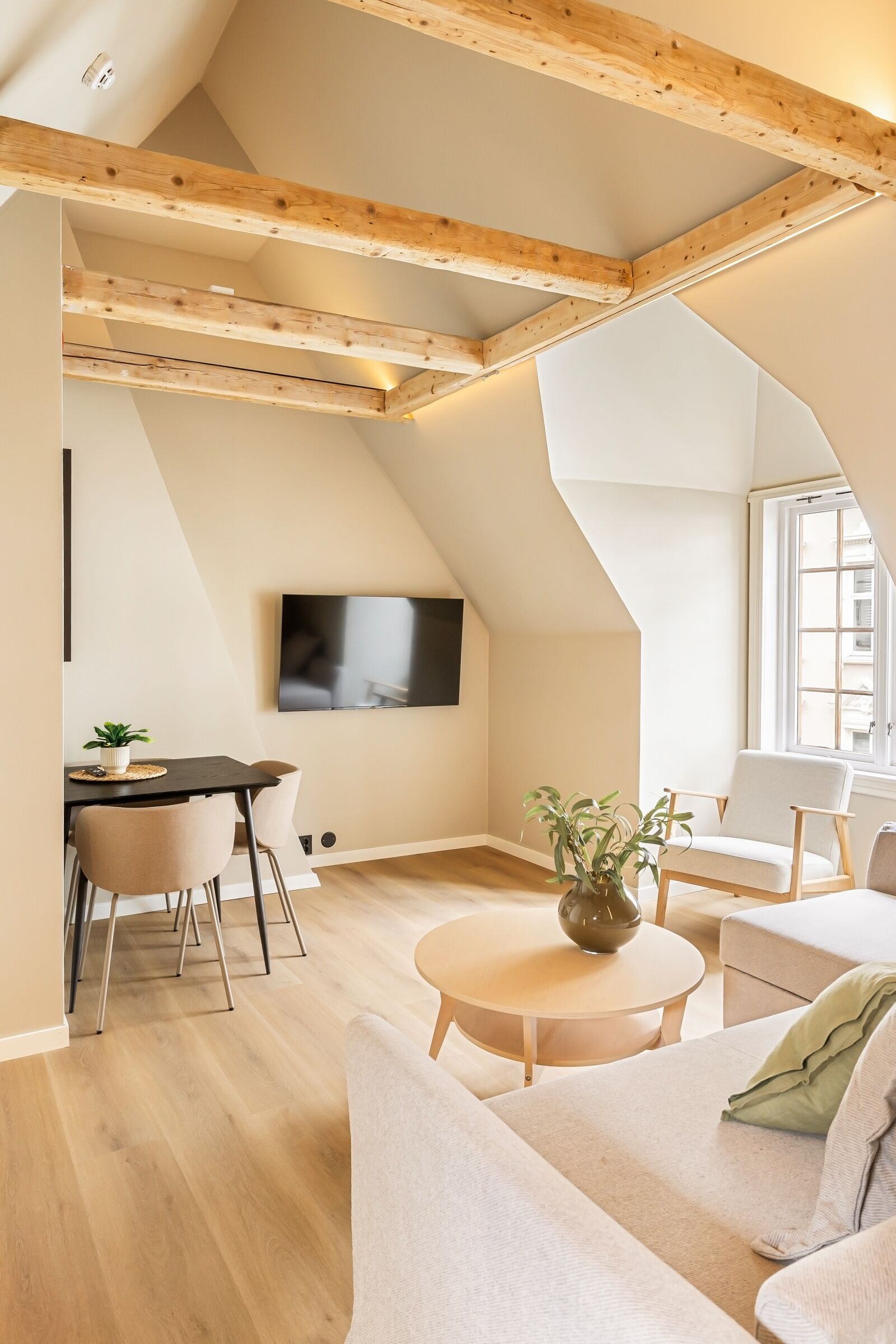 Un loft moderno con vigas de madera a la vista, un televisor de pantalla plana, un comedor y un espacio de descanso acogedor.
