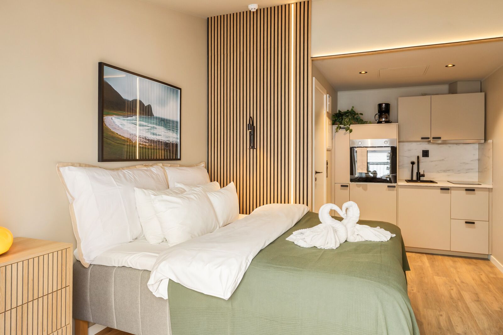 Una habitación de hotel moderna con una cama, un cuadro, una zona de cocina y vistas al mar.