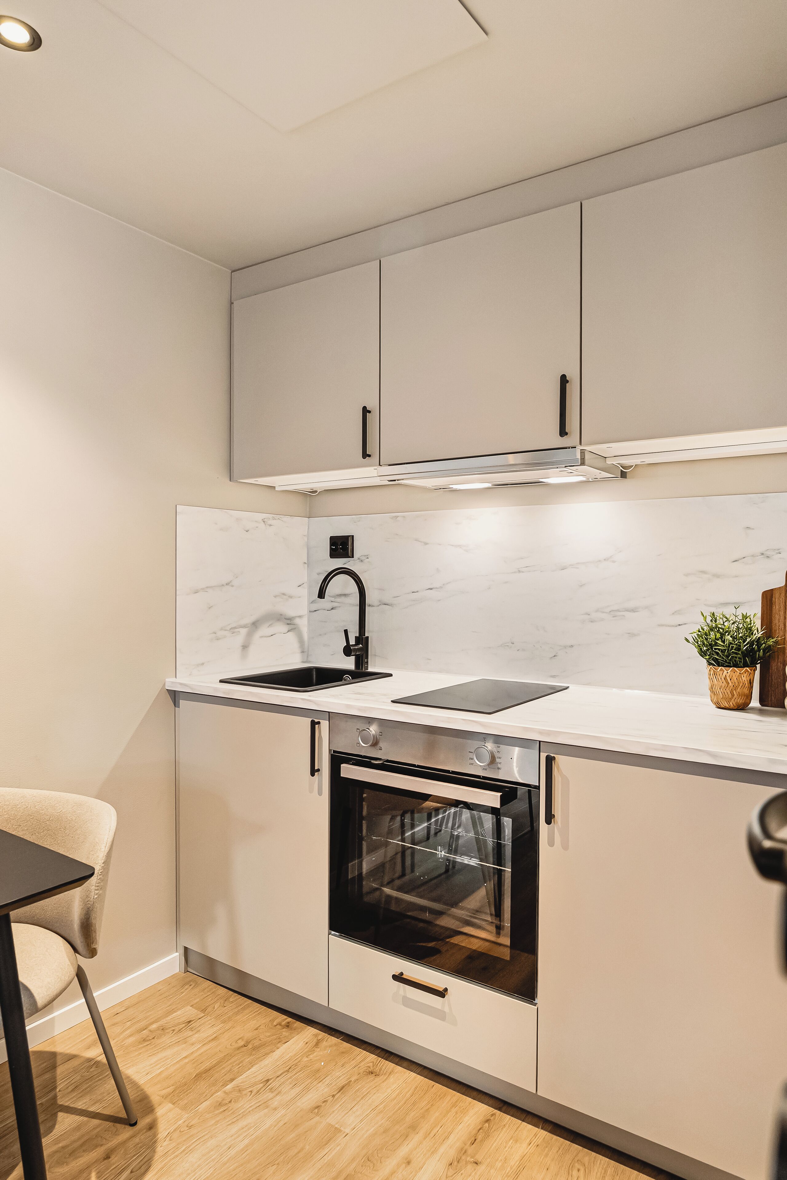 A modern kitchen with white cabinets, a black faucet, and a built-in oven.