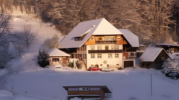 A large, multi-story building with a snow-covered roof, surrounded by a snowy landscape and trees.