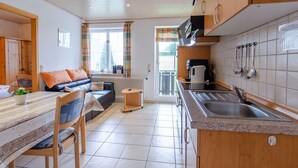 A modern kitchen with a sink, cabinets, and a dining area with a table and chairs.
