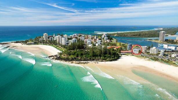 An aerial view of a coastal resort with beachfront properties, a pier, and a dense cluster of buildings.