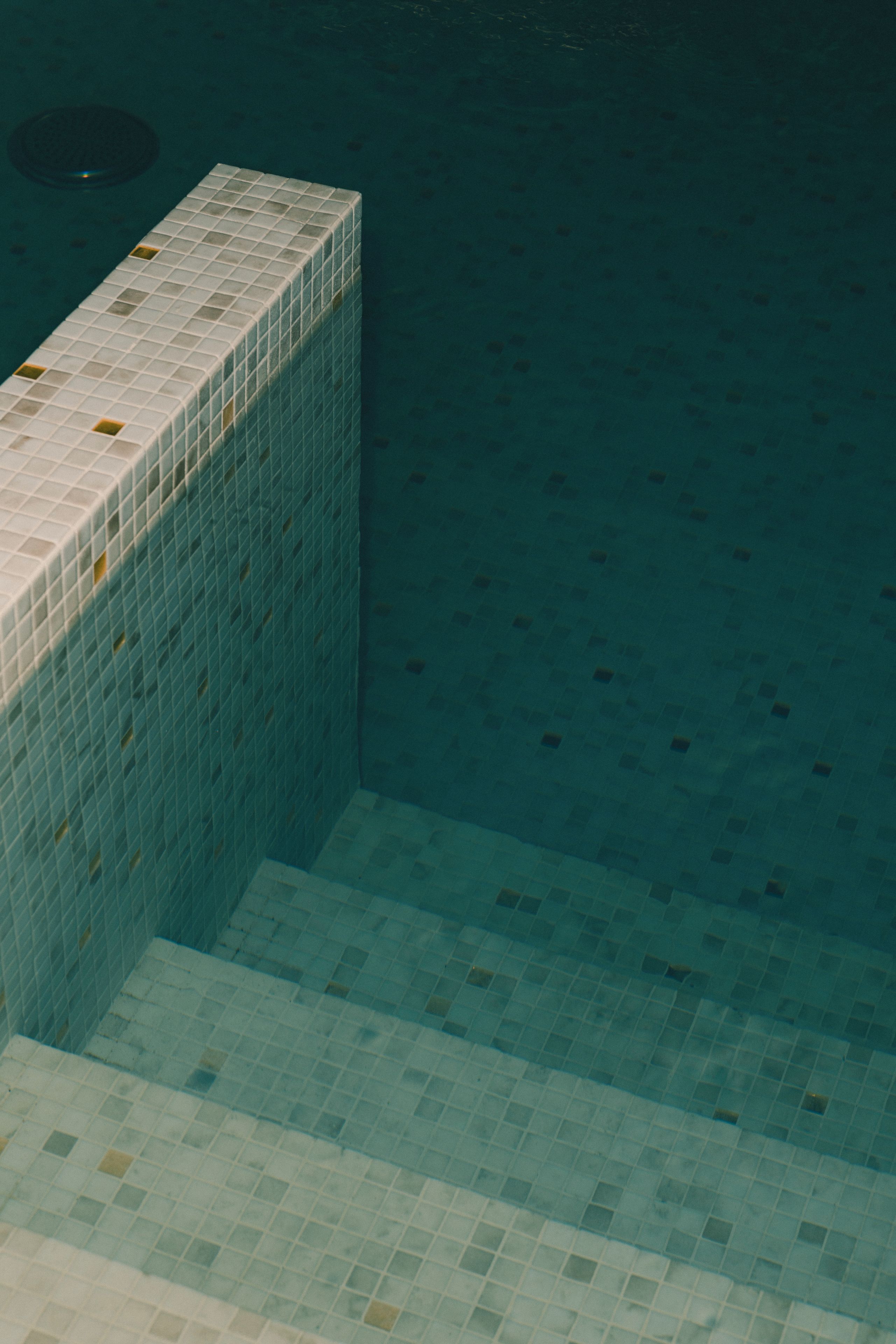 Una piscina con baldosas, línea de agua transparente y escalones para entrar.