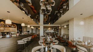 A restaurant with multiple dining tables, chairs, and a bar area with bottles and glasses. - Hotel & Spa Amoria La Baule, A Member Of Radisson Individuals (La Baule-Escoublac)