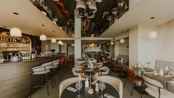 A restaurant with multiple dining tables, chairs, and a bar area with bottles and glasses.
