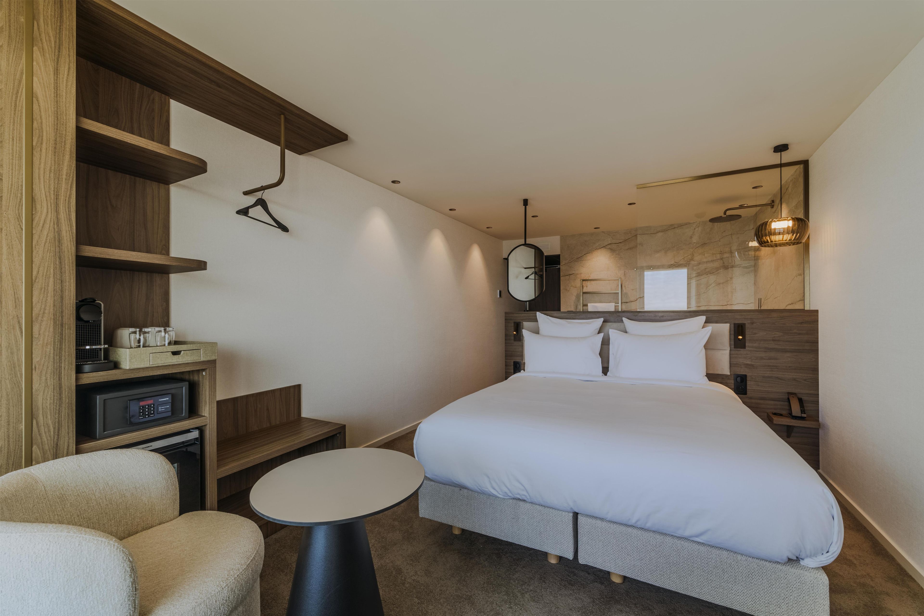 Une chambre d’hôtel comprenant un lit, un bureau, une chaise, une petite table et un miroir.