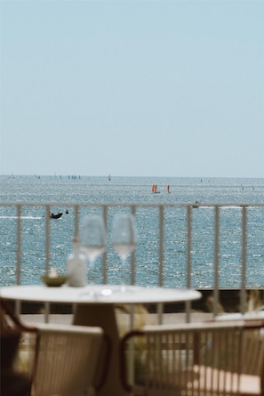 A view of the sea from a balcony with a railing, a table with a glass, and a chair. - Hotel & Spa Amoria La Baule, A Member Of Radisson Individuals (La Baule-Escoublac)