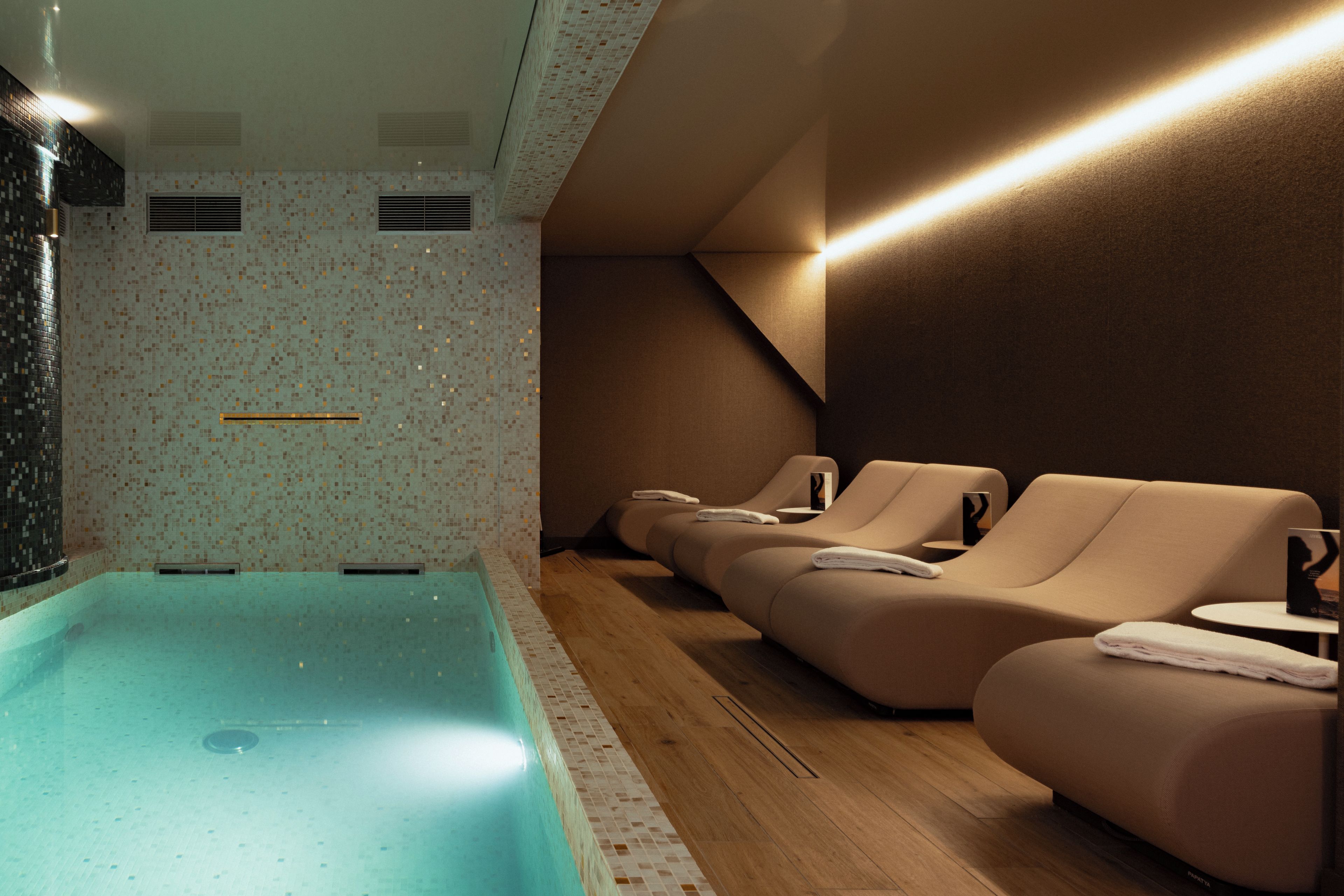 A spa area with a pool, seating, and a tiled wall.