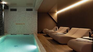 A spa area with a pool, seating, and a tiled wall.