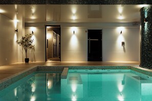 A swimming pool with tiled edges, a potted plant, and wall-mounted lights. - Hotel & Spa Amoria La Baule, A Member Of Radisson Individuals (La Baule-Escoublac)