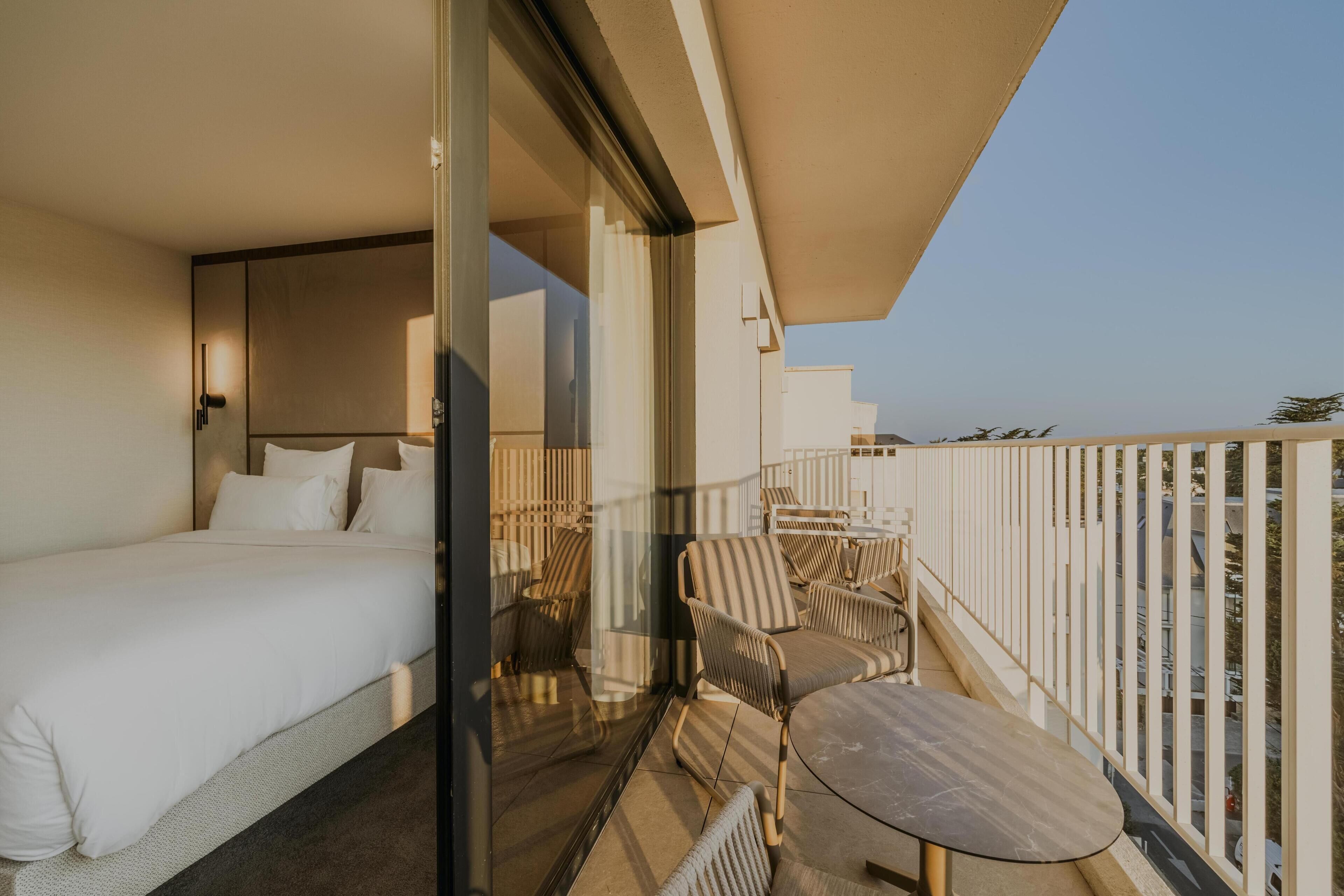 Un balcon avec un lit, une table et des chaises.