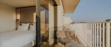 A balcony with a bed, a table, and chairs.