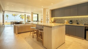 Una cocina moderna con una isla grande, taburetes de bar y vistas a la playa.