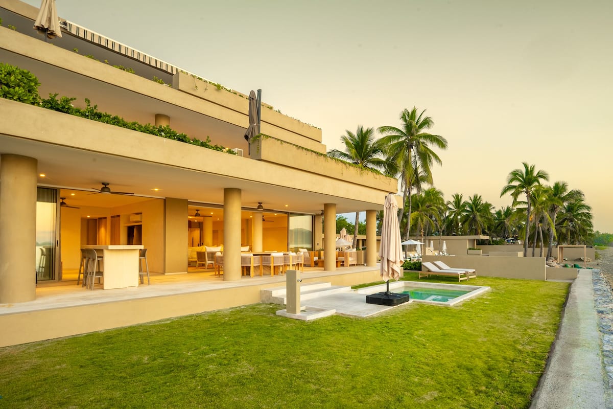 A modern hotel with a pool, outdoor seating, and palm trees.