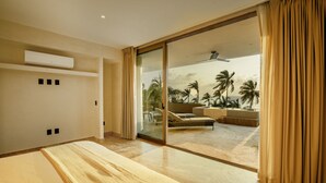 Habitación de hotel moderna con un gran ventanal corredero que da a un balcón con vistas a palmeras y una piscina.
