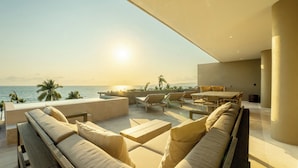 Un moderno espacio lounge al aire libre con vista al océano, que incluye un conjunto de sofás, sillas y una mesa.