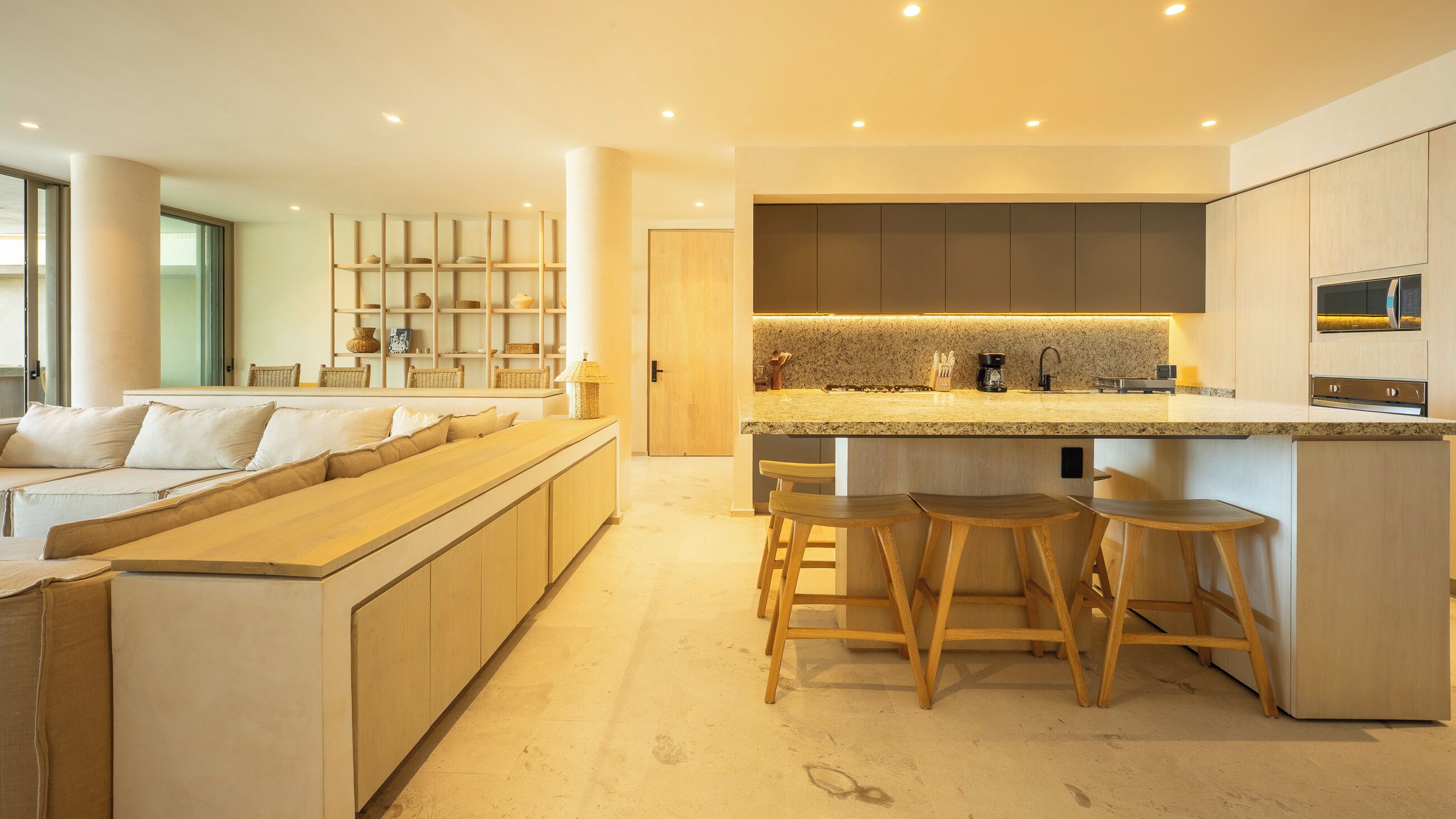 A modern kitchen with a central island, bar stools, and built-in appliances.