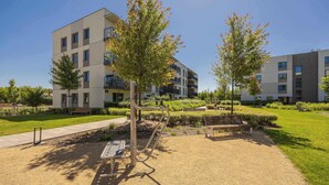 A modern outdoor area with a fitness station, benches, and a well-maintained lawn.