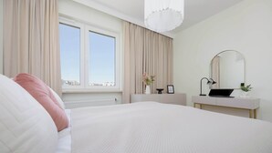 A modern bedroom with a large bed, a bedside table with a lamp, a mirror, and a window with curtains.
