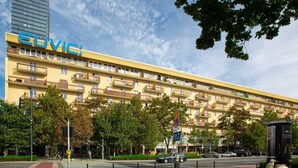 Un hôtel jaune à plusieurs étages, doté de balcons et d’une enseigne indiquant « EUVI ».