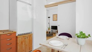 Una cocina moderna con refrigerador empotrado, armarios de madera y un comedor con una mesa para dos.