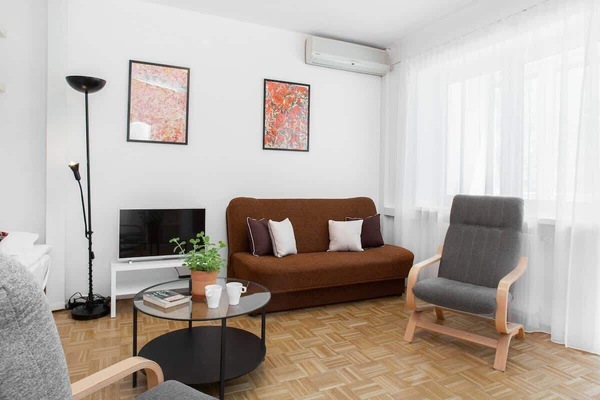 A compact, stylish living area with a brown sofa, coffee table, and a TV.