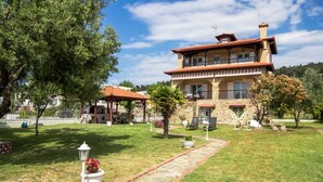 A two-story stone building with a red-tiled roof, a covered patio, and a stone pathway leading to the entrance.