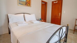 A neatly made bed with white linens and pillows, a wooden headboard, and a painting of butterflies on the wall.