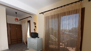 A hotel room with a bed, a small desk with a television, a wardrobe, and a balcony with a view. - Azalia House by Rentalspro (Nea Propontida)