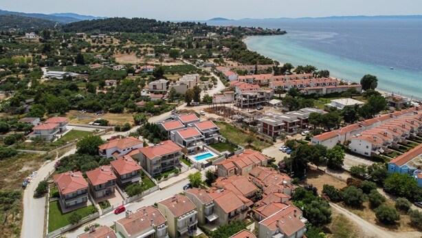 An aerial view of a coastal residential area with houses, a beach, and a clear sky. - Artistic Vibe by Rentalspro - Nikiti Halkidiki (Sithonia)