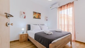 A modern bedroom with a wooden bed, white bedding, a bedside table with a lamp, and artwork on the walls. - Artistic Vibe by Rentalspro - Nikiti Halkidiki (Sithonia)
