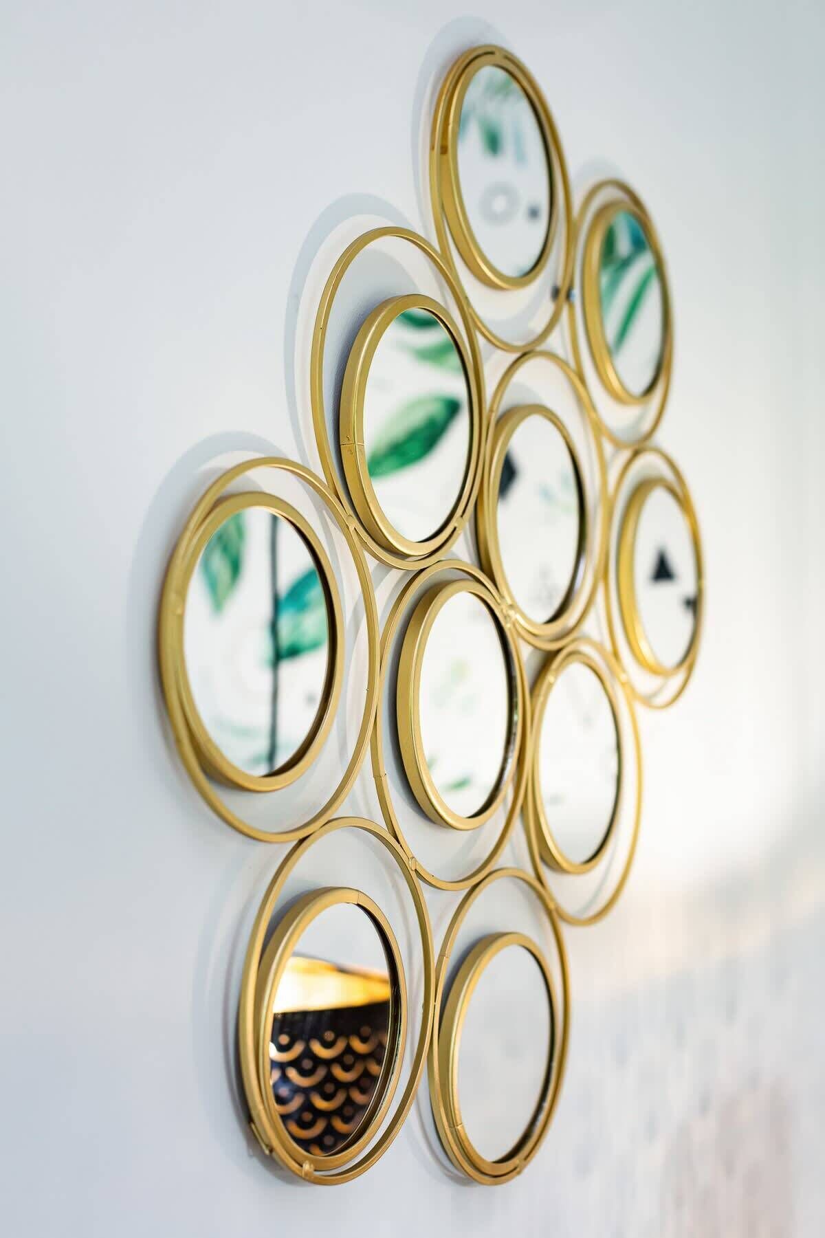 Eine Wanddekoration aus runden Spiegeln mit goldfarbenen Rahmen.