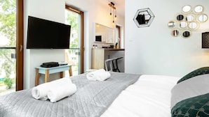 A hotel room with a bed, a TV, a desk, and a view of the outdoors.