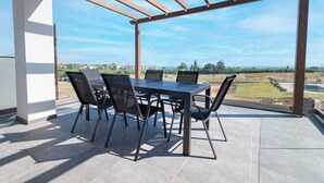 A covered patio with a table and chairs, offering a view of the surrounding landscape. - Asteria Mare 1 by Travel Pro Services (Polygyros)