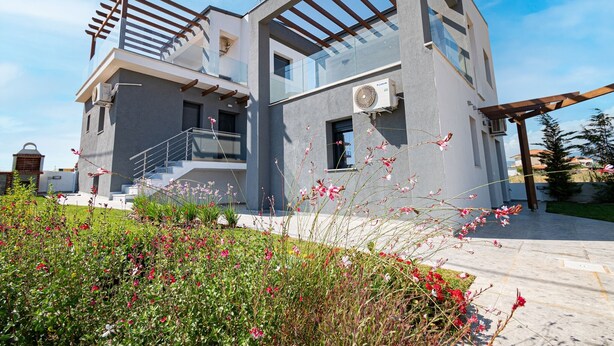 A modern two-story house with a balcony, a pergola, and a garden with flowers. - Asteria Mare 1 by Travel Pro Services (Polygyros)