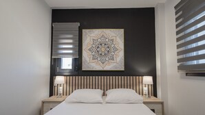 A neatly made bed with two pillows, a wall-mounted artwork, and two bedside lamps. - Asteria Mare 1 by Travel Pro Services (Polygyros)