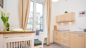 Una cocina moderna con comedor, que incluye una cuna blanca, una mesa de comedor con un florero y vistas de la ciudad a través de amplias ventanas.