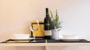 A table with a bottle of Pinotage wine, a glass, and two bowls on a white tablecloth. - Cozy Studio in the Center | Close to Central Station (Warszawa)