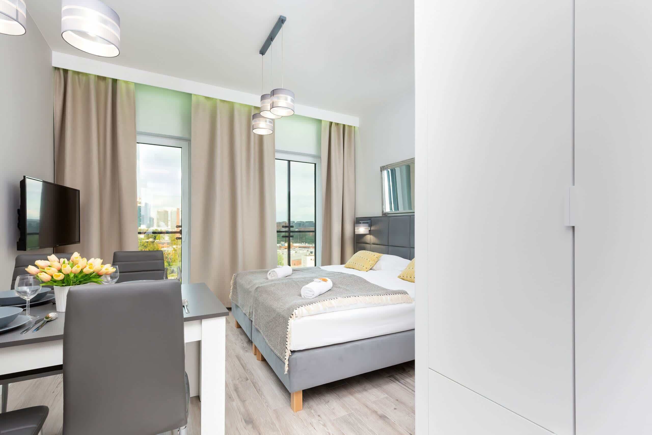 Habitació d'hotel moderna amb llit, escriptori, cadira, televisió de pantalla plana i vista a la ciutat.