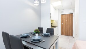 A modern dining area with a rectangular table set for four, black chairs, and a small potted plant.
