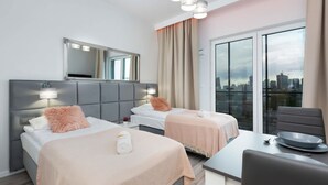 A modern hotel room with two beds, a dining table, and a city view.