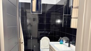 A modern bathroom with a toilet, sink, and shower. - B&S Luxe Living (Kampala)