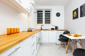 Functional kitchen with white furniture and wooden worktop. There is a table and chairs underneath the hay.