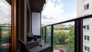 Ein Balkon mit Korbmöbeln und freiem Blick auf die umliegenden Gebäude und die grüne Umgebung.