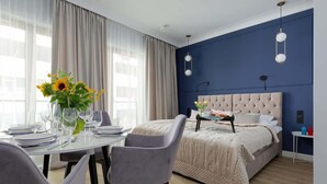 Ein modernes Schlafzimmer mit einer gepolsterten Kopfstütze, einem Esstisch gedeckt mit Tellern und Gläsern, und einer Vase mit Sonnenblumen.