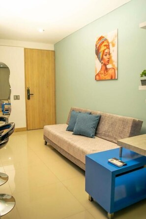A modern living room with a sofa, a coffee table, and a painting on the wall. - Migar Alojamientos (Cali)