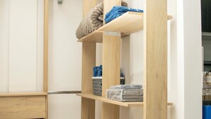 Ein Holzregal mit gefalteter Kleidung und einem blauen Korb.